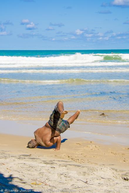 Imagem de uma rapaz jogando capoeira nas areias da Praia de Jeribucaçu.